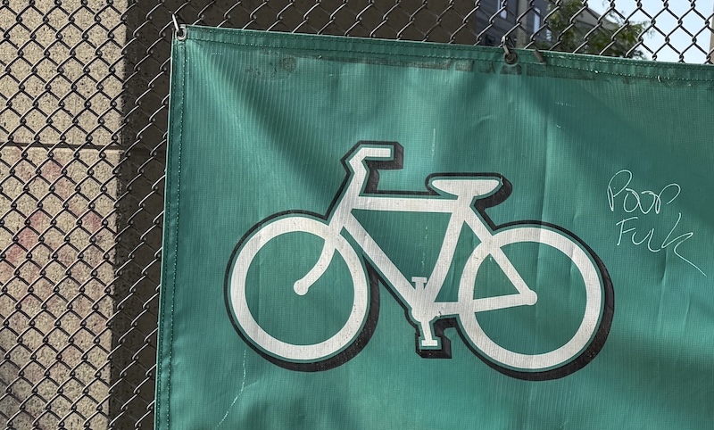 photo i took of a bicycle store banner that someone wrote "POOP FUCK" on