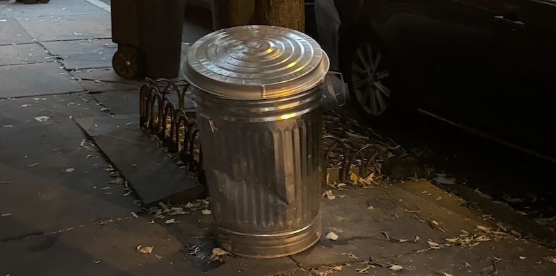 photo of an old-school aluminum garbage pail like the one oscar the grouch lives in, sitting out on a neighboring street for trash pickup