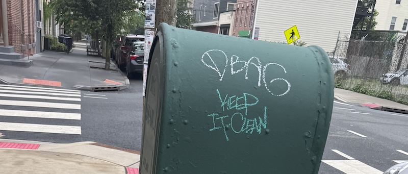 photo of a green usps carrier box that someone wrote "dbag" in white chalk and below it someone wrote "keep it clean" in green"