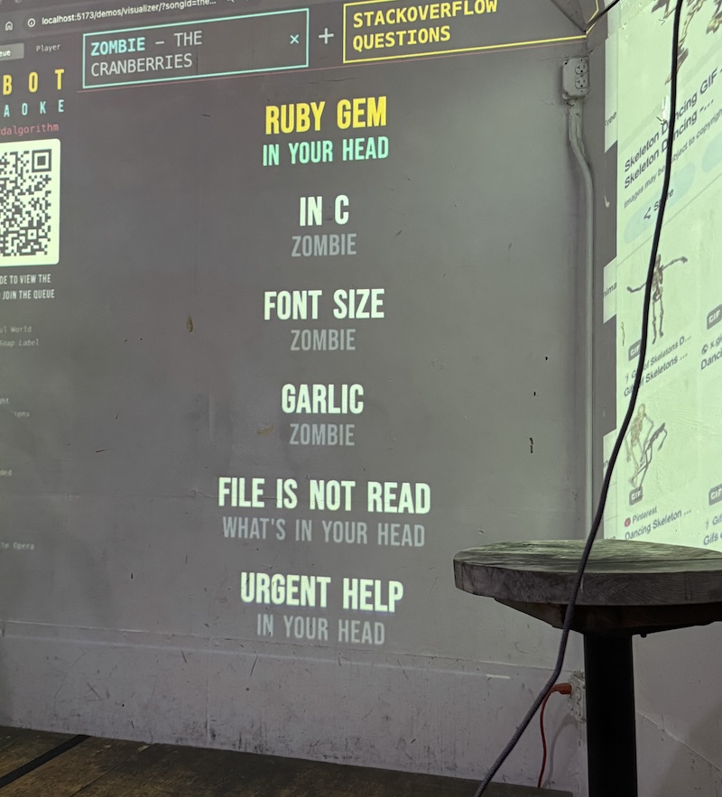 photo of the wonderville stage with robot karaoke projected onto it. the song is zombie by the cranberries and the lyrics are generated from stackoverflow questions.