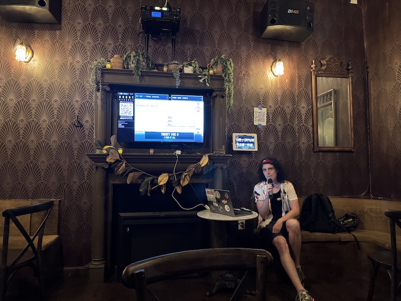 photo of jamie setting up robot karaoke in a fancy, dark speakeasy that has a big television on the wall, which is where we're showing robot karaoke