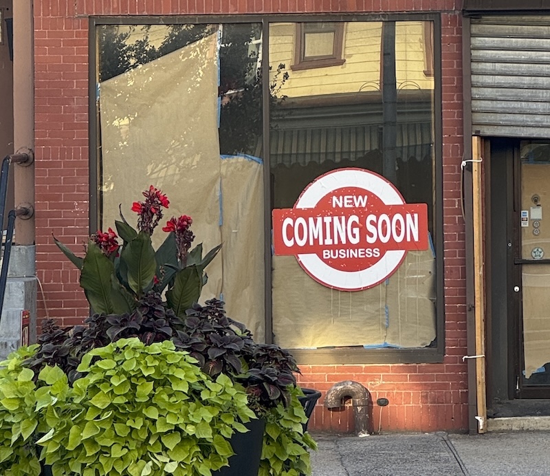 photo of a papered-up business with a sign that says "COMING SOON" with "new" above it and "business" below it. one could not tell what this "business" is