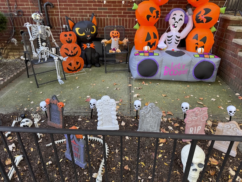 photo of a neighbor's front lawn filled with all sorts of halloween decorations like tombstones and skeletons