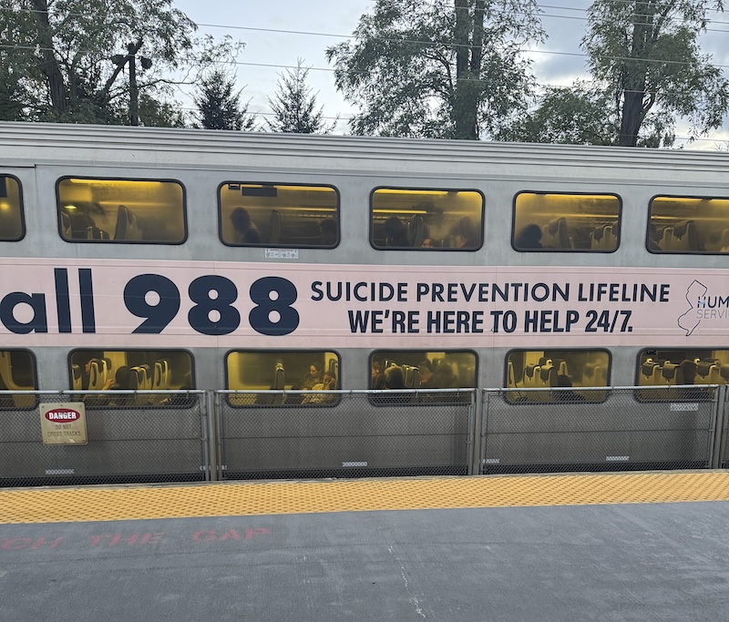 photo of a train on the opposite tracks wrapped with a psa for the 988 suicide prevention hotline