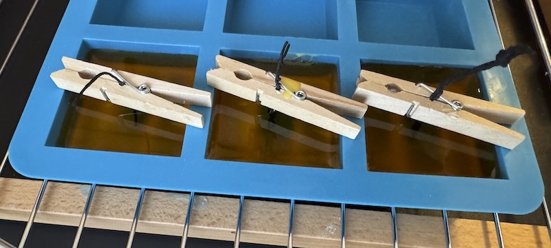 melted beeswax wicked in a blue silicone mold of 3 rectangular prisms