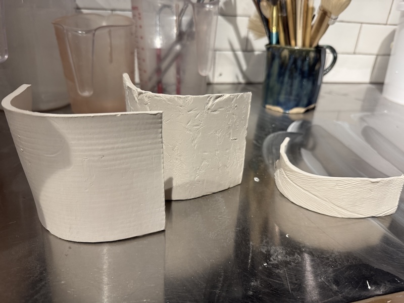 photo of three test tiles i made with different textures, before pre-glazing