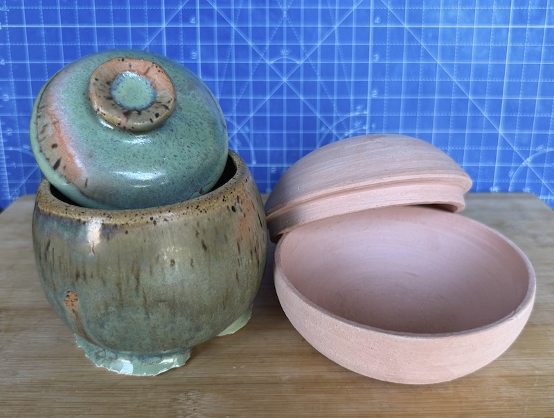 a photo of two closed vessels with lids i made. one is glazed with peach and green and the glaze is gloopy on the bottom. the other vessel is bisqueware - i've not glazed it yet