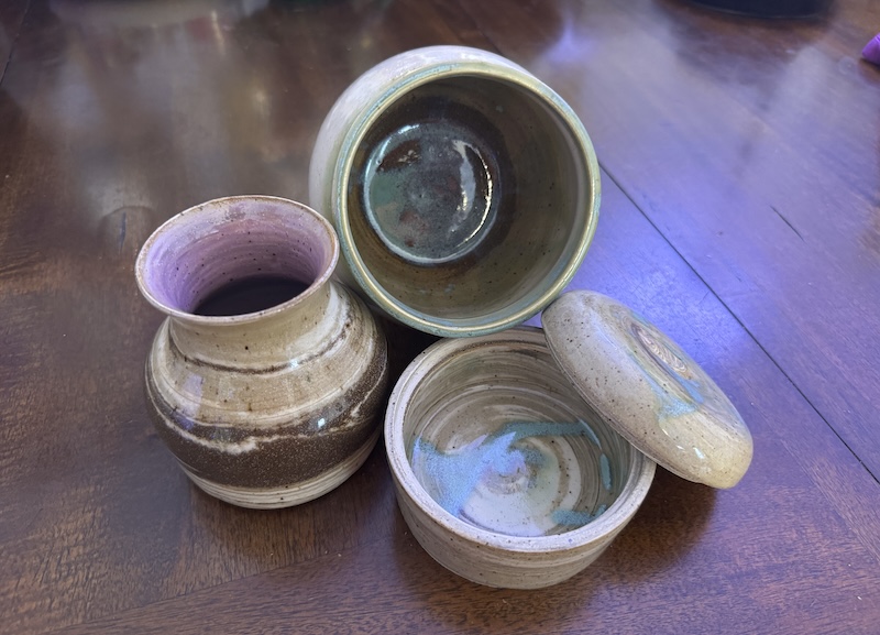 a photo of three marbled clay pieces. one's a pot i turned so you can see some cool green inside splotches. the splotches appear inside the closed vessel that i have a lid hanging off the side of. the small vase has a light purple inside.