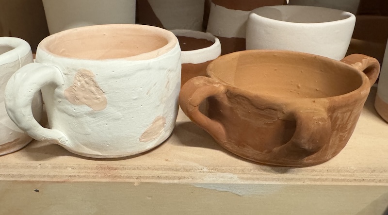 photo of two of my mugs glazed but not fired yet, so they look pastel