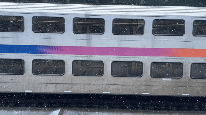 gif of snow falling in front of the side of a nj transit double-decker train