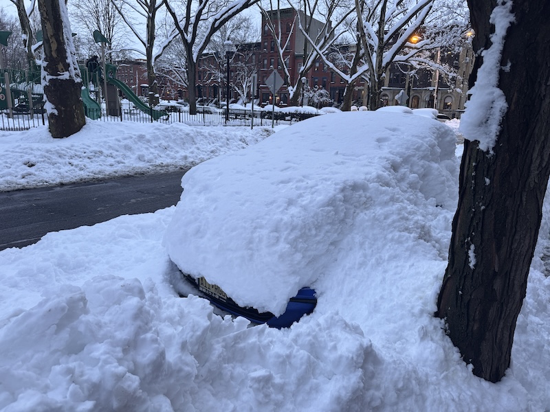 photo of the snow outside and there's a car completely buried in it