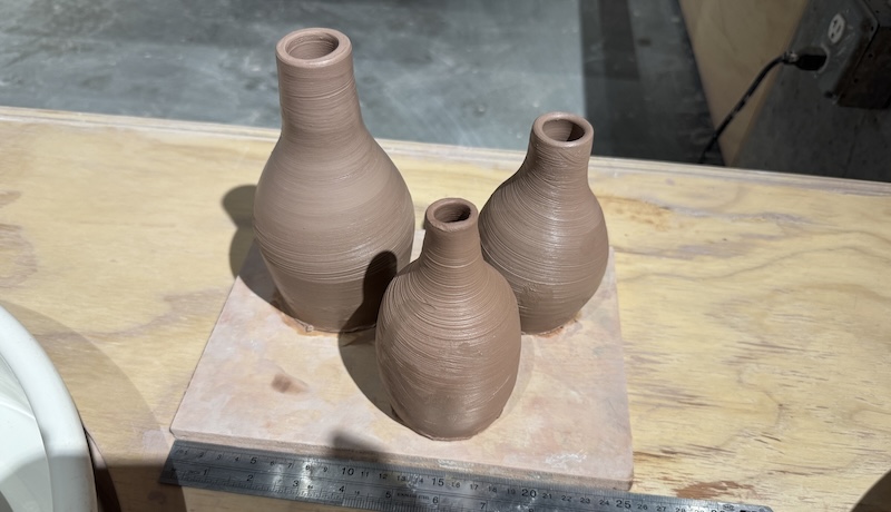 three freshly thrown bud vases and bottle that i made drying on a small board