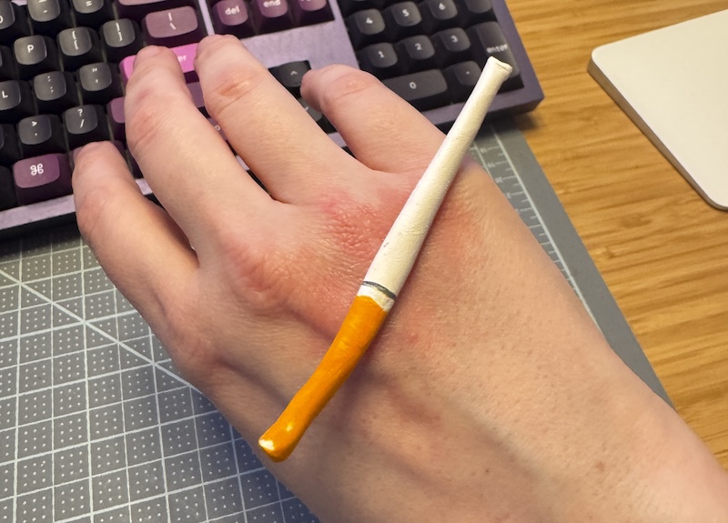 photo of the top of my hand on my desk. i have a clay cigarette balancing and there's red underneath it because the fake ciggie is covering my fresh oven burn