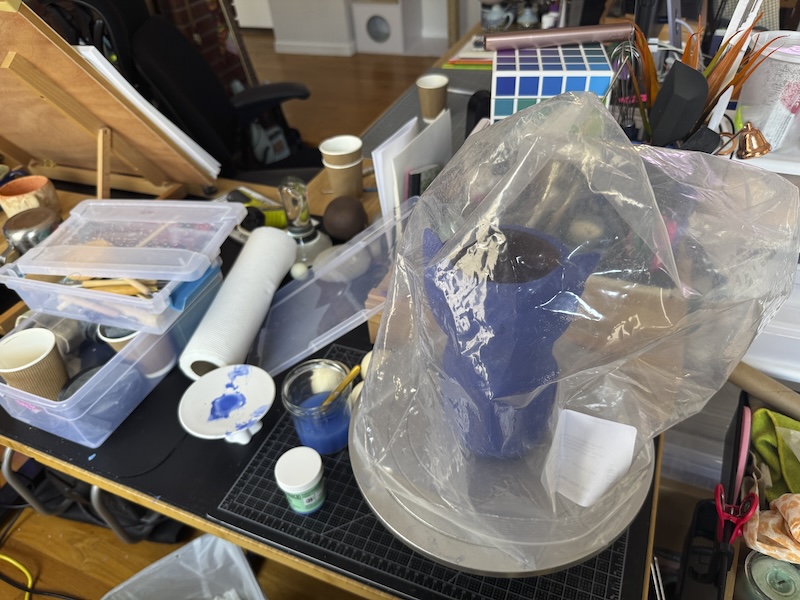 photo of my very messy desk covered in candle-making stuff and ceramic sculpting stuff