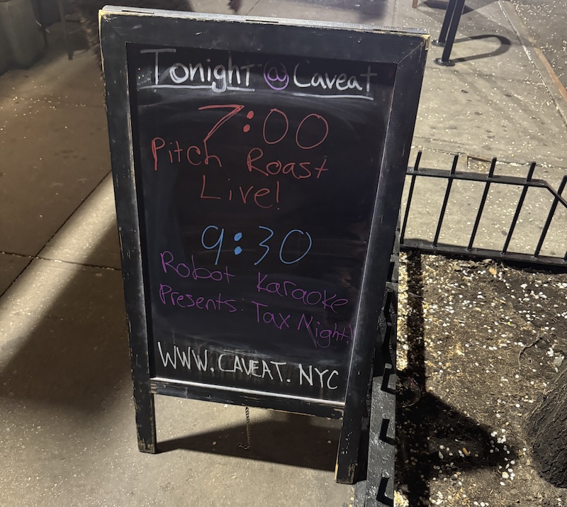 photo of a sandwich board outside caveat in nyc that says robot karaoke was starting at 9:30pm