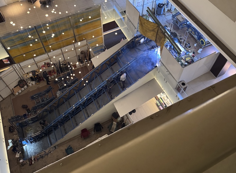 photo of a gutted escalator in repair, taken from the 5th floor of a hotel that is panopticon style