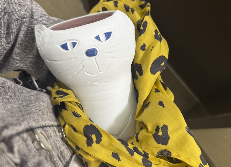 photo of a pre-glaze fired cat vase i've got in a bag, held like a baby
