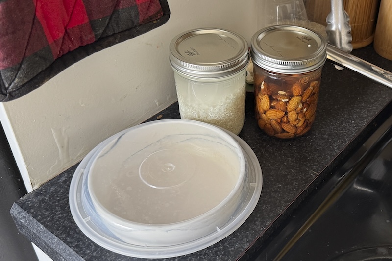 photo of a bowl with my sourdough starter next to two mason jars of rice and almonds soaking in my kitchen