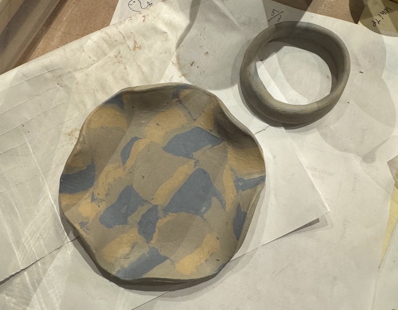 photo of a clay dish i'm making using the nerikomi technique, with clays of blue, tangerine and white in an abstract pattern