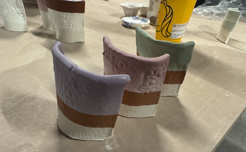 photo of a few newly-dipped-in-glaze test tiles on a shelf in the ceramics studio