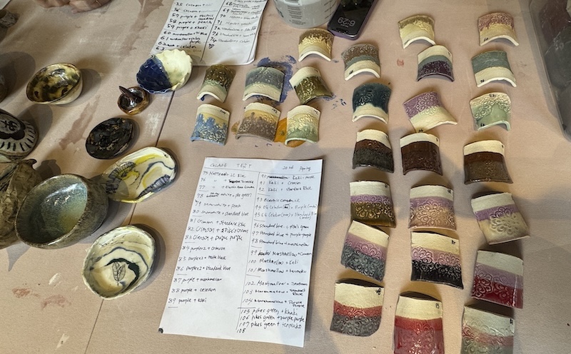 photo of a bunch of glaze fired ceramic tiles laid out on a table with a list of our recipes