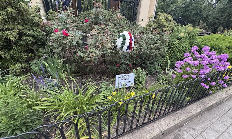 photo of the hamilton park jersey city gazebo with lots of flowers and an arrangement with a sign that says "welcome world to hamilton park"