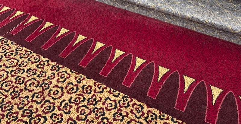 photo of the new yorker hotel 2nd floor carpeting that has a weird cheetah print then a pattern that's the mcdonalds M arches repeating and then the stairs are a completely different pattern and color scheme. they all clash