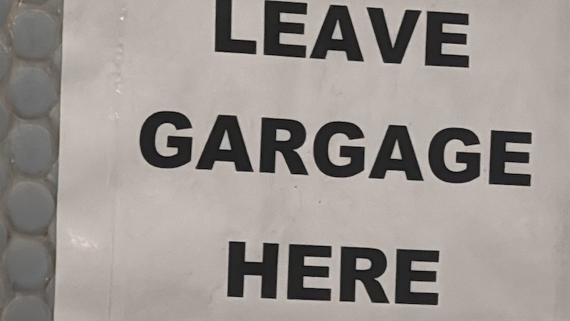 zoomed-in photo of a sign that says "LEAVE GARGAGE HERE"