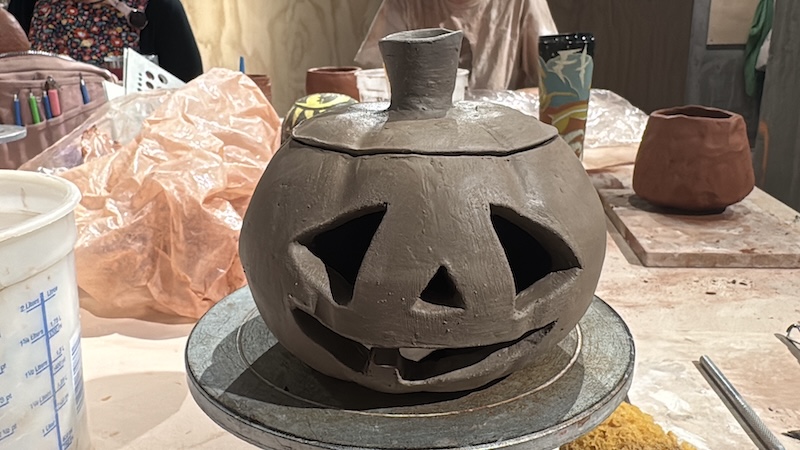 a photo of a clay jack o'lantern i hand-built and carved, sitting on a banding wheel and leather-hard