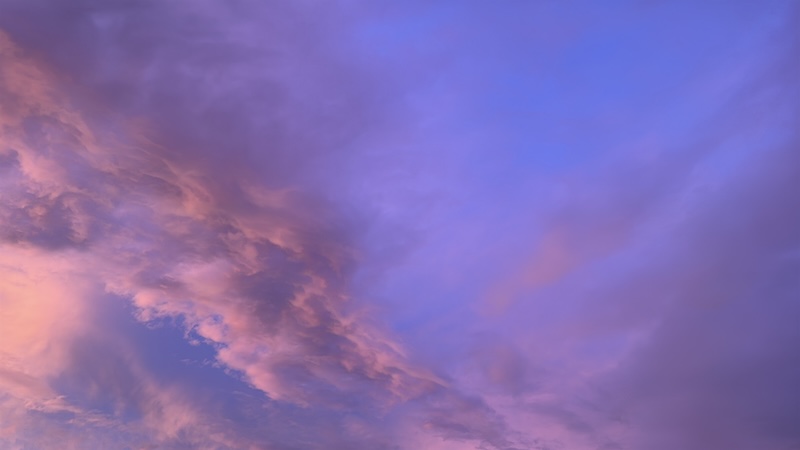a photo of the beautiful sky that's deep blue with mostly pink and orange and gray clouds as the sun sets the night a huge storm is coming