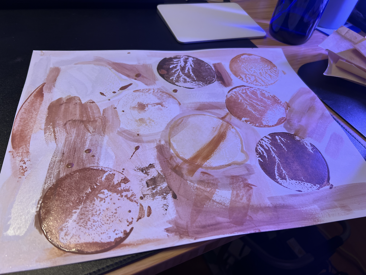 photo of a painting that’s from my wiping a round glass muller covered in brown watercolor being rested on and pulled across a piece of paper