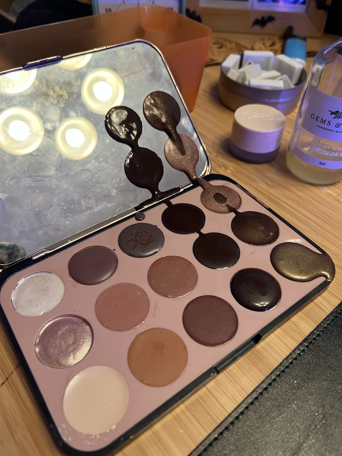 photo of my eyeshadow palette but each eyeshadow is watercolor that’s still wet and because the palette accidentally closed, 4 of the newer paints are smeared on the mirror part of the palette