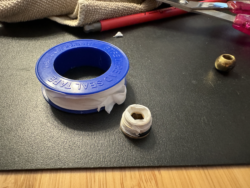 photo of the washer with thread tape around it, sitting on my desk next to a spool of thread tape
