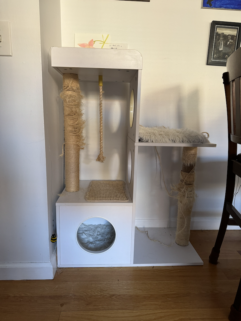 photo of a white cat tree that has 2 different-leveled cratching posts and the rope is falling off because of pumagreg's destruction