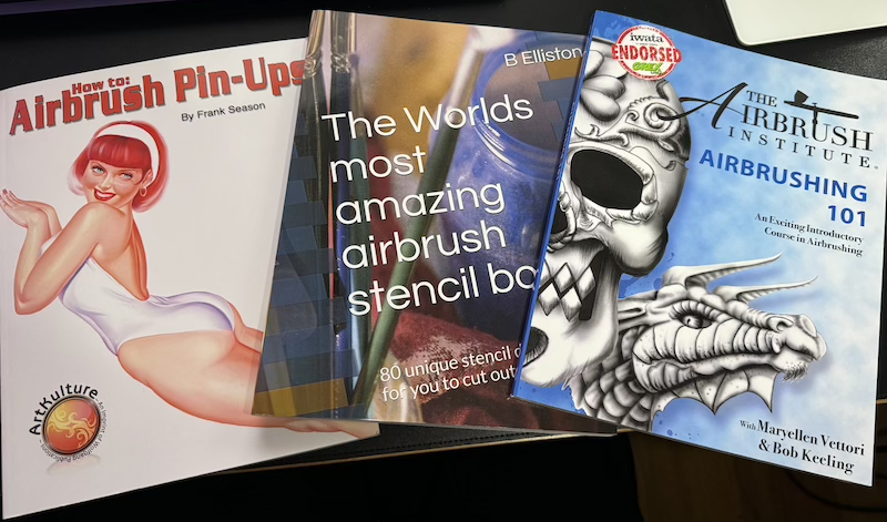 photo of three paperback books: "how to: airbrush pin-ups", "the world's most amazing airbrush stencil book" and "airbrushing 101"