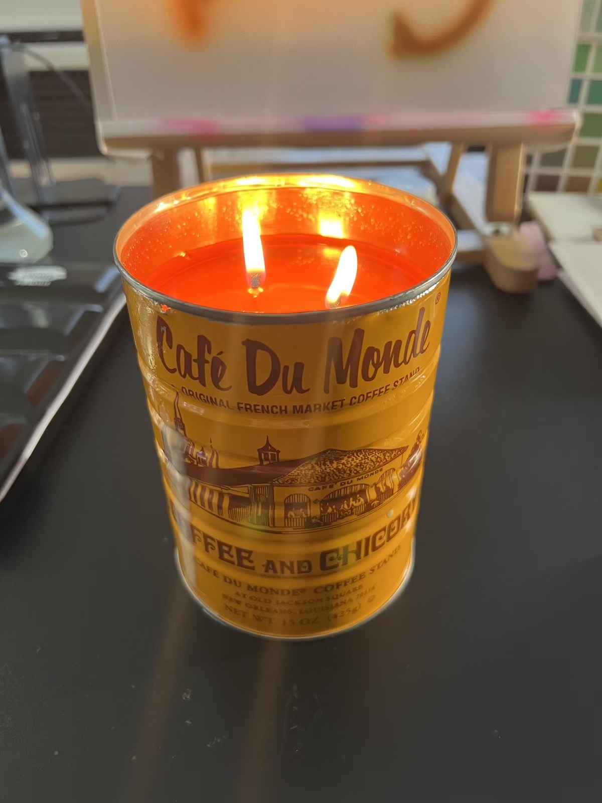 photo of an orange, double-wicked (and lit) candle made from a cafe du monde coffee tin