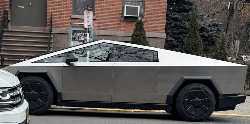 photo i took of a cybertruck parked illegally in front of a sign celebrating veterans