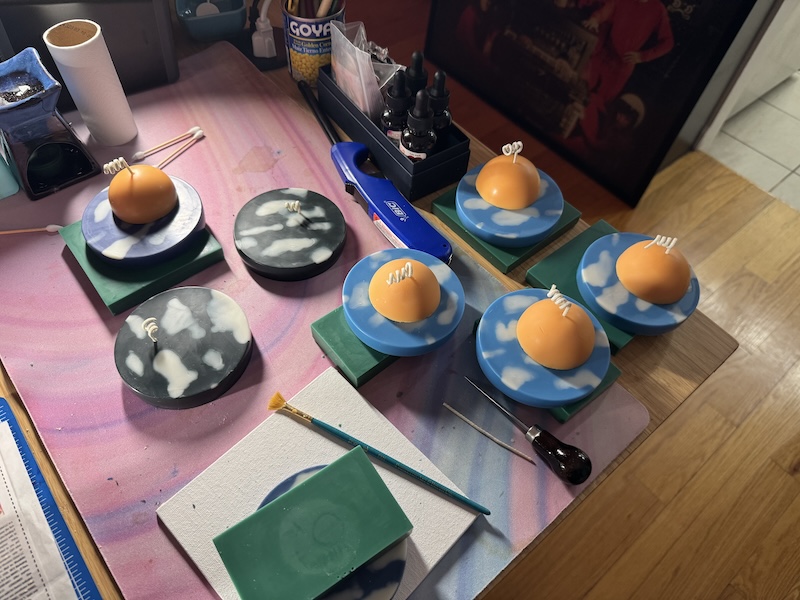 photo of my candle-making station (my desk) with a bunch of candles of the sky with white clouds