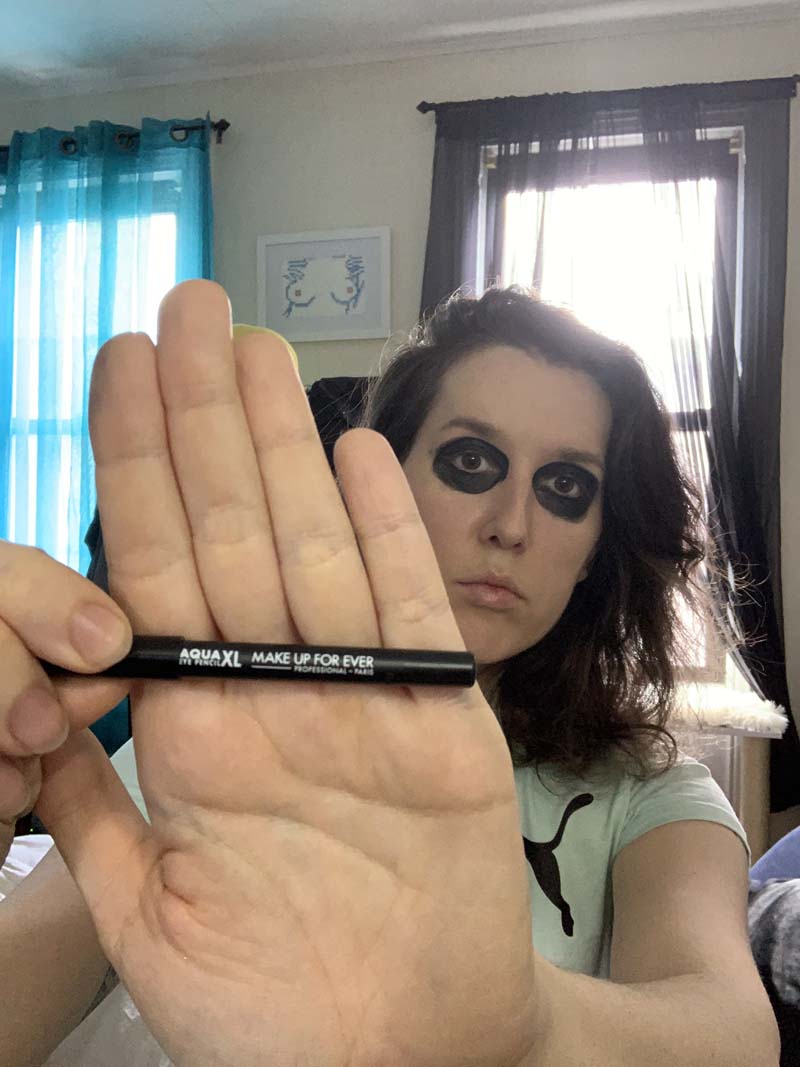 me with my eyes colored black all around like alice cooper and i'm holding up my eyeliner