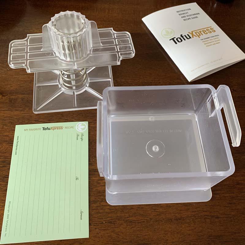 the parts of the tofuxpress laid out along with a recipe card and notepad it came with