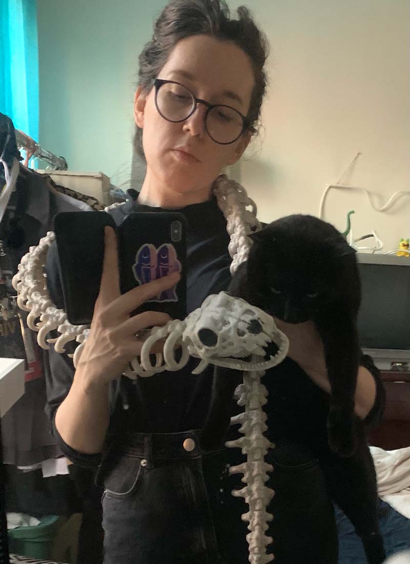 mirror selfie of me holding my black cat and also i have a snake skeleton as a scarf
