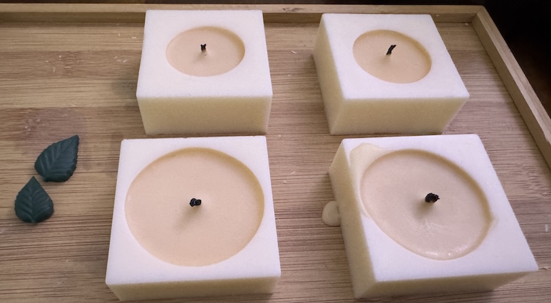 four white cubic candles partially burned with different wicks during a test