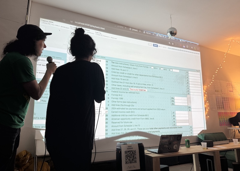 photo of jamie and sarah singing "dreams" karaoke with a big screens showing a 1040 tax form which is where the lyrics are generated from