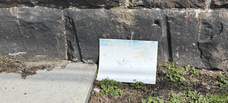 that child's painting laid against the embankment wall i posted last week except it had rained and a lot of the paint washed off, but the canvas had not been moved