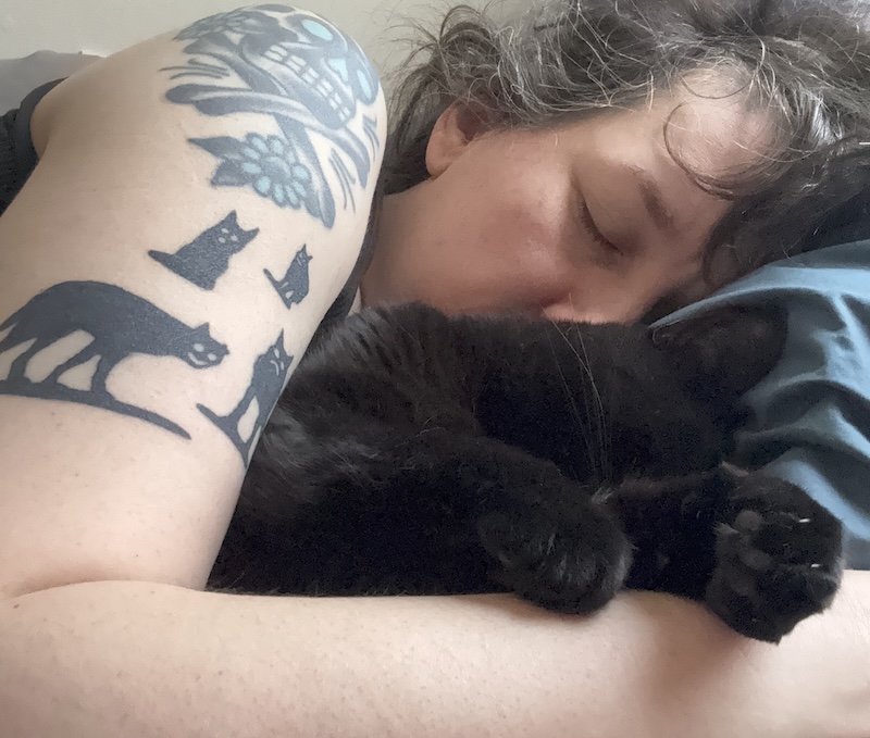 photo of me sleeping as big spoon to my little spoon and black cat pumagreg, you can see my little black cat tattoos and one of them is puma