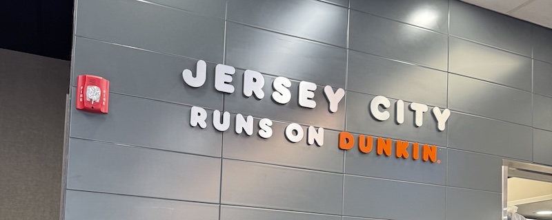 photo of the wall of the downtown jersey city dunkin that says "jersey city runs on dunkin"