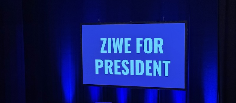 photo of a large screen on a theater stage that says "ZIWE FOR PRESIDENT" on it