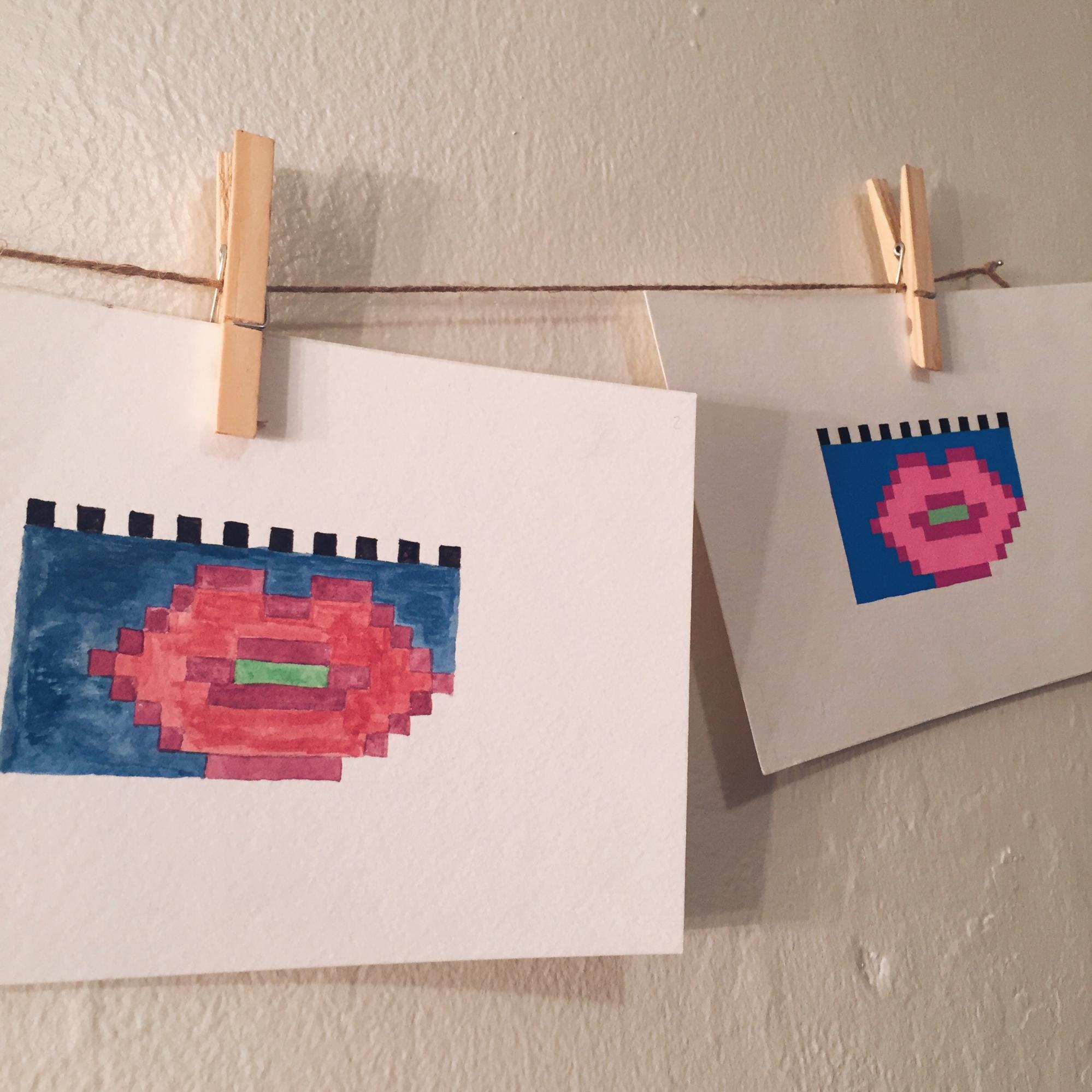 two pixel lip drawings hanging on my wall, one is watercolor and the other is the same drawing but with ink