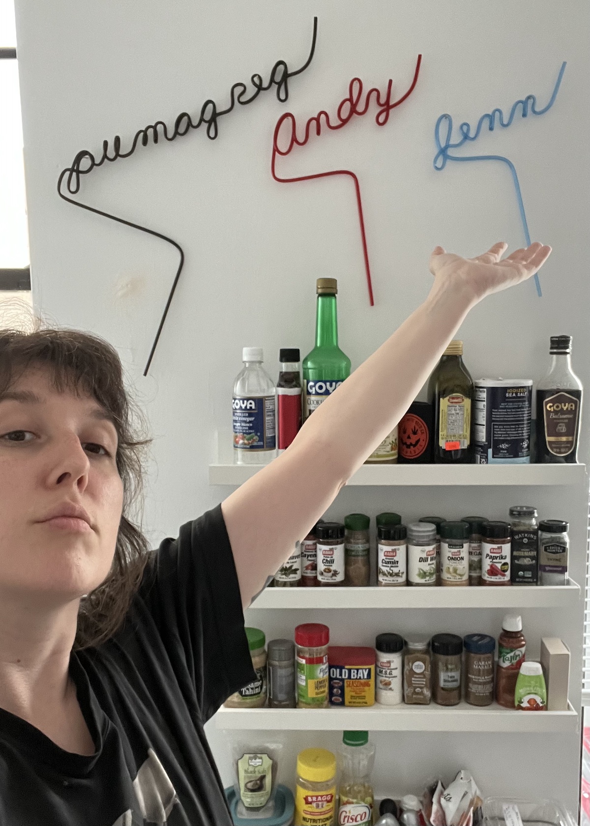a selfie where i'm posting dramatically in front of a wall of spice shelves and above them are 3 crazy straws that spell out "andy" "pumagreg" and "jenn"