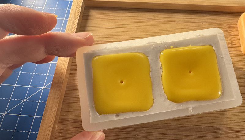 photo of the butter mold filled with hardened yellow wax and i poked each tab with a hole to put a wick in